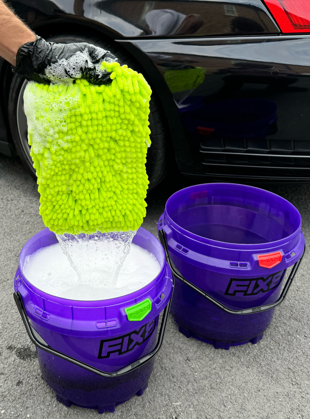 Detailer working around vehicle with bucket system